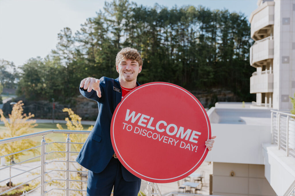Student holding a welcome to discovery day sign