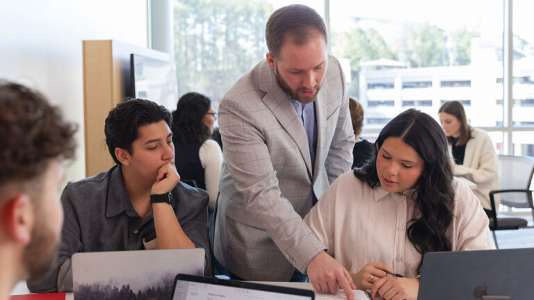 undergraduate students sitting and laughing on campus green
